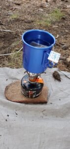 Pictured here is a pocket stove on a small propane canister. Sitting on top is an extremely lightweight aluminum cup. These items take up very little space in my camping bag. It is also a very simple set up with no fuss. 